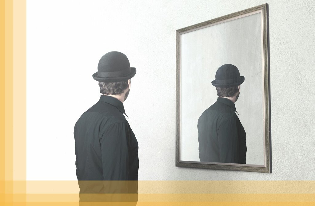 Mann mit Hut vor einem Spiegel