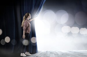 Eine Person schiebt einen Bühnenvorhang zur Seite, dahinter scheinen Bühnenscheinwerfer auf die Bühne. Das Bild versinnbildlicht die Anekdote, die Mark Poppenborg in seinem Artikel „Was wird hier für ein Spiel gespielt?“ erzählt.